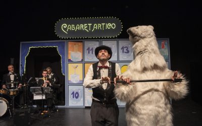 Un attore e un attore vestito da orso polare ballano insieme con un bastone in mano